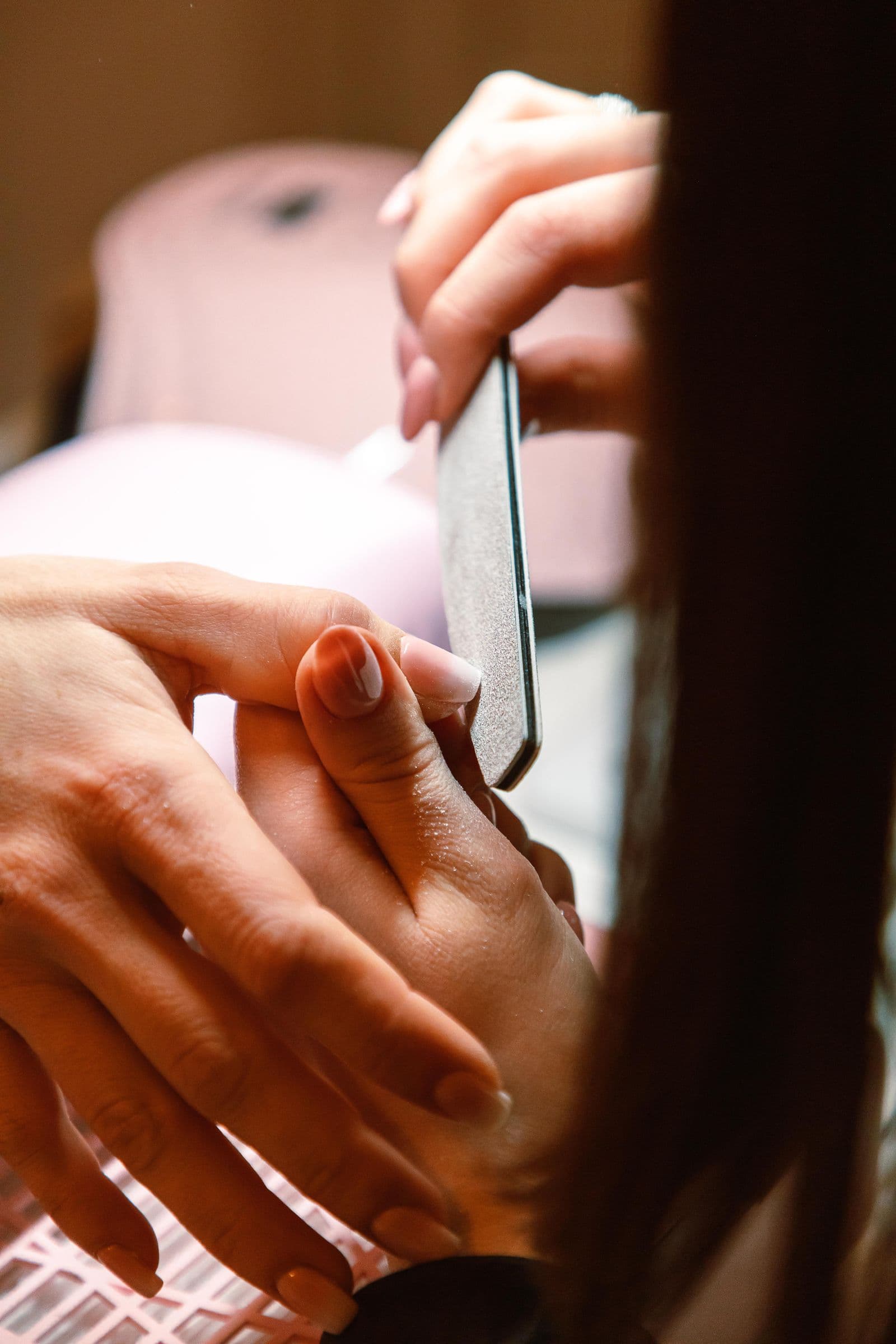 Close-up of a manicurist filing a client's nails