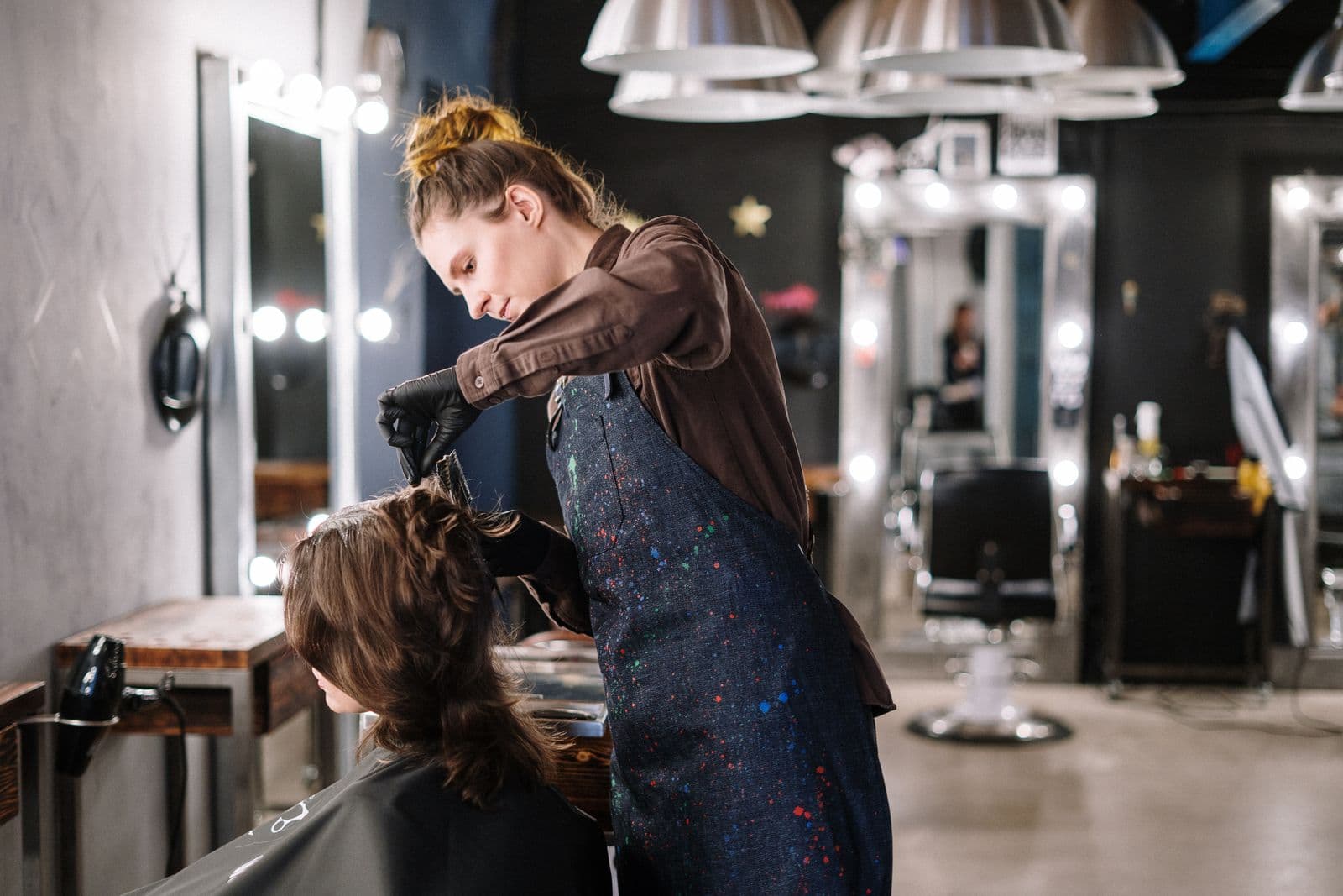 A hair stylist applying color treatment to a client in a modern salon